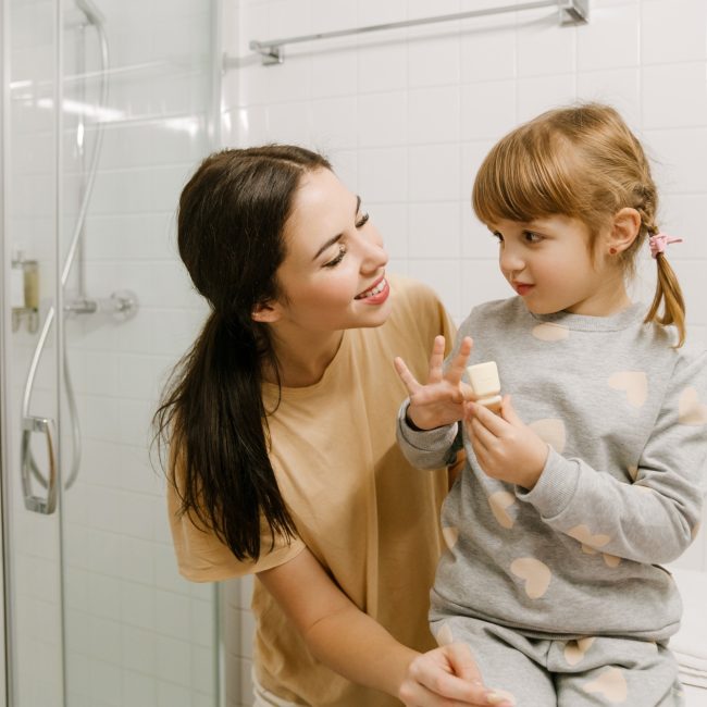 White woman smiling while doing makeup together in bathroom